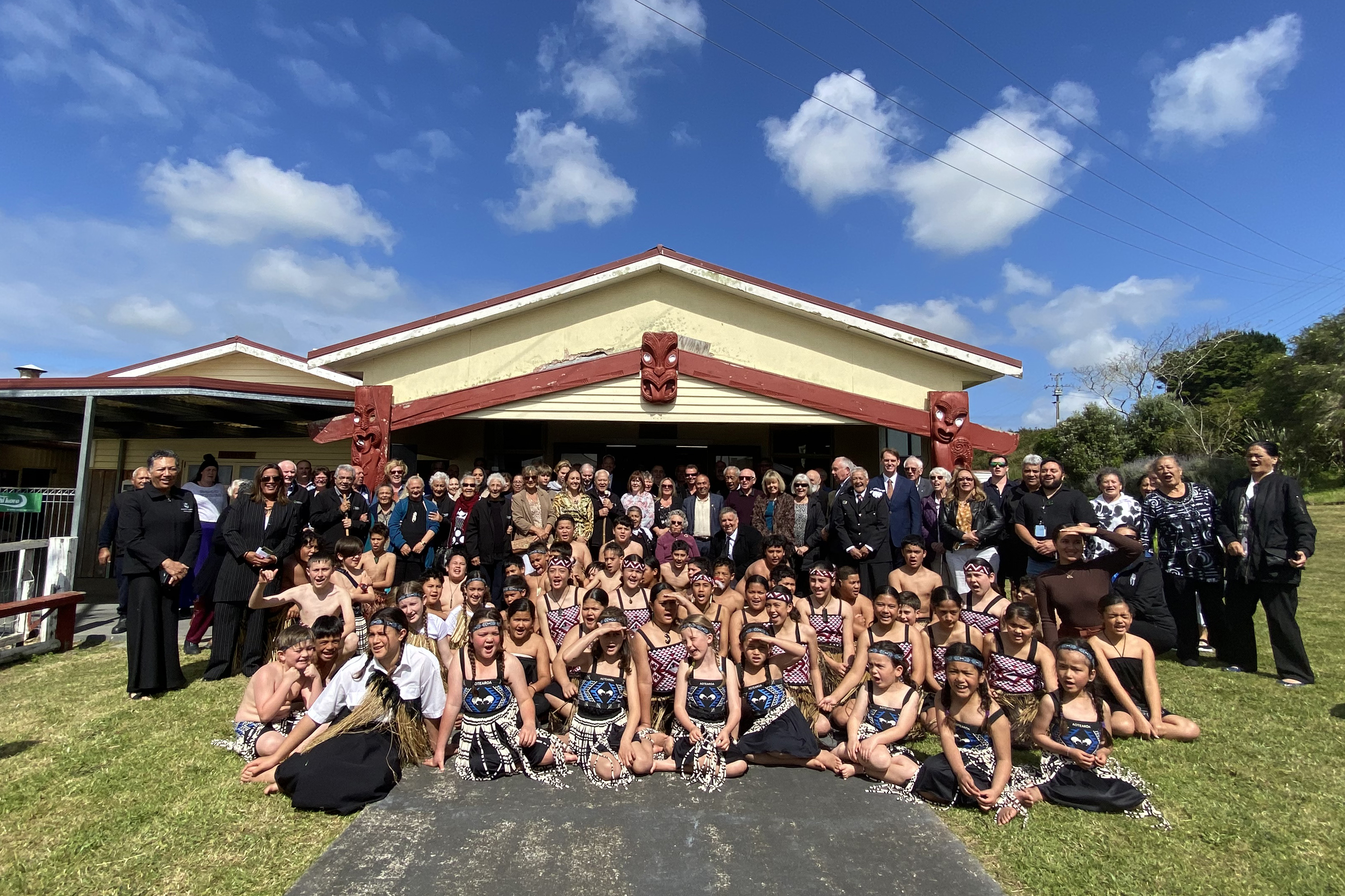 Group of people in front of marae whare
